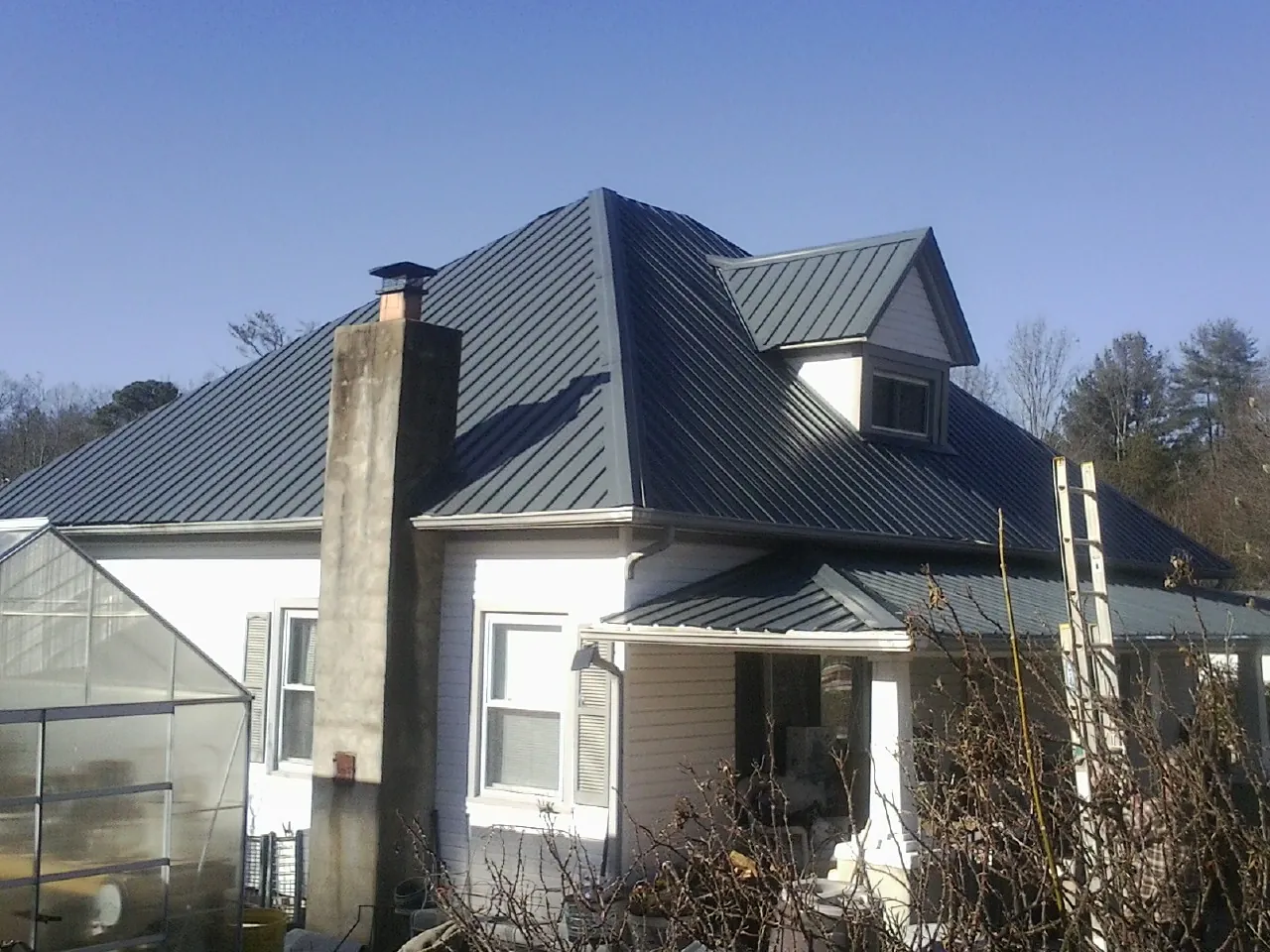 Dark blue standing seam metal roof on a white farmhouse with dormer — Slate & Tile Roof Repair by Roofing Brothers in Collinwood