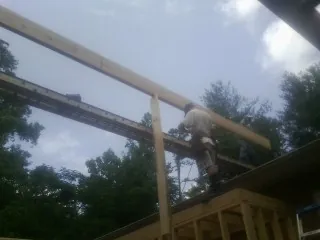 Carpenter setting a ridge beam over a new addition frame — Ice Dam Removal by Roofing Brothers in Collinwood