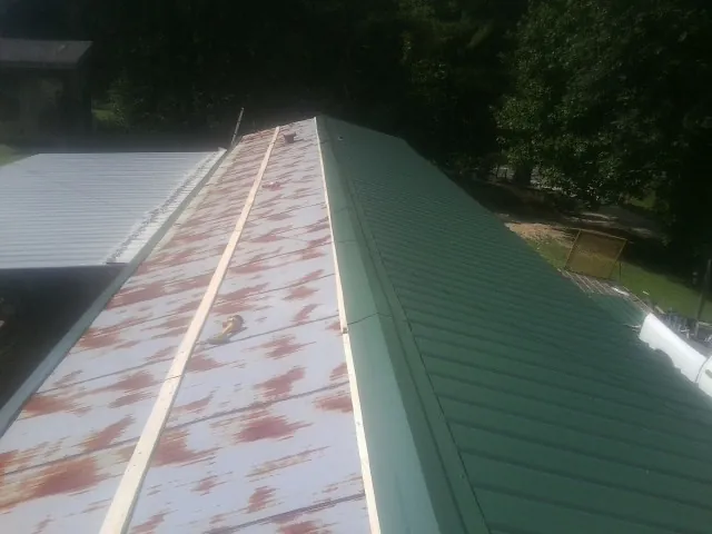 Old rusted panels beside newly installed green metal roofing — Wind Damage Roof Repair by Roofing Brothers in Collinwood