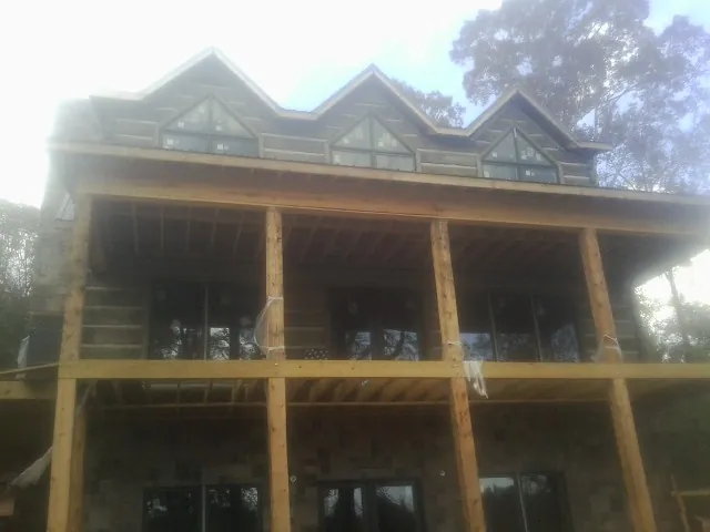Dormers and porch framing on a large log home under construction — Roof Coating work by our crew in Collinwood