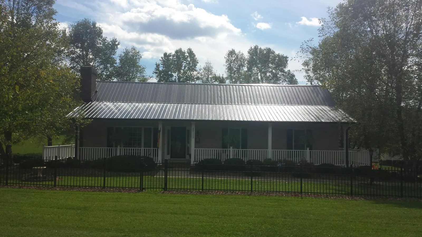 Gray metal roof on a brick ranch with a full width front porch — Gutter Guard Installation work by our crew in Collinwood
