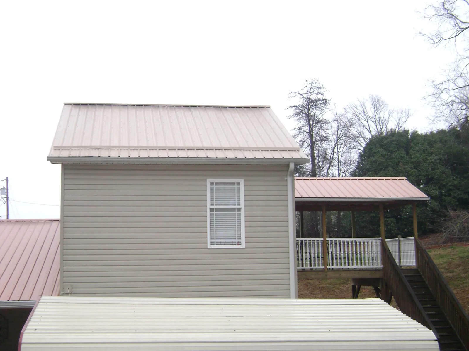 Tan metal roofs on a two story addition and attached porch, from a Roof Replacement job in Collinwood