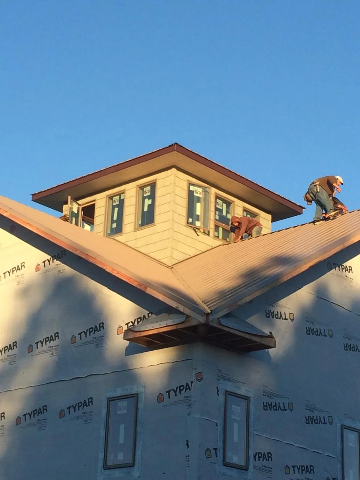 Roofers working around a rooftop cupola on a new metal roof at sunset — Roof Waterproofing in Collinwood by Roofing Brothers